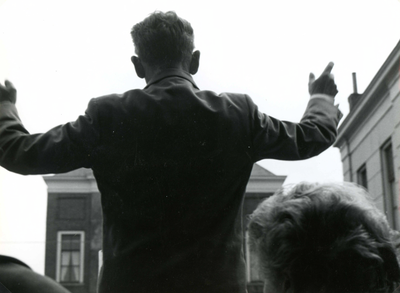 BR_KONINGINNEDAG_1961_018 Wout van Soest dirigeert de schooljeugd tijdens het zingen op de Markt; 1 mei 1961