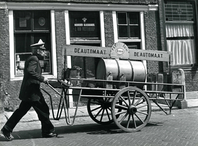 BR_LANGESTRAAT_031 Olieman P. van Adrighem loopt met zijn oliekar 'De Automaat' door de Langestraat; ca. 1965