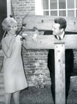 BR_MUSEUM_ACTIVITEITEN_016 Een vrouw sluit de schandpaal waar een man zijn hoofd in steekt; ca. 1970