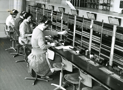 BR_VOORSTRAAT_183 De telefoondienst in het postkantoor van Brielle, dames zitten achter de posten; April 1958