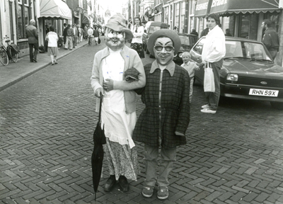 BR_VOORSTRAAT_528 Tijdens de Kolder Koopavond staat een duo verkleed in de Voorstraat. Rechts is mevrouw Postuma; 5 juni 1986