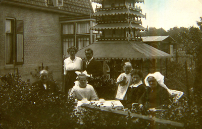 OV_FHGVANITERSONLAAN_13 Gezin in de tuin van het huis Rijlaan 189. Op de achtergrond een duiventil; ca. 1920
