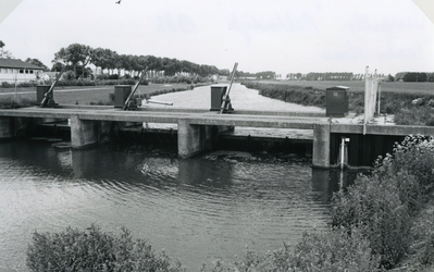 VP_ACHTERDIJK_029 Waterstuw in hoofdwaterafvoer door Voorne naar gemaal Trouw. Op de achtergrond de Rijksstraatweg; ca. 1980