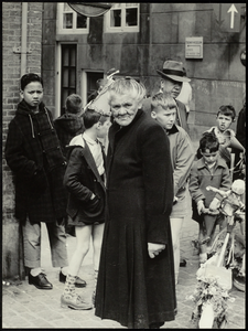 FOTO_GF_C108 Mevrouw Louwe, bezorgster van de Brielsche Courant, tijdens Koninginnedag in de Koopmanstraat; 1962