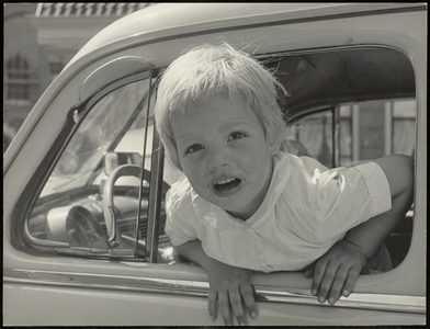 FOTO_GF_C120 Portret van een jongen, hangend uit een autoraam; ca. 1962