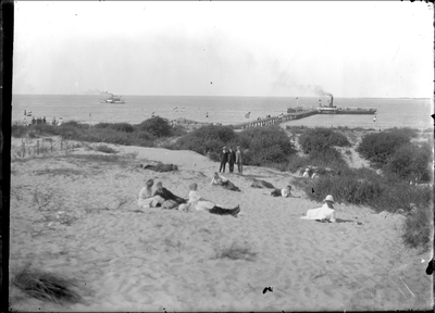 GN2332 Badgasten in de duinen, met de aanlegsteiger op de achtergrond; ca. 1920