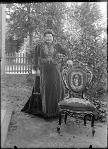 GN2880 Een vrouw in dure kleding staat naast een luxe stoel; ca. 1910