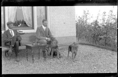 GN4023 Twee mannen op een tuinbank met twee honden (mogelijk familie Boers); ca. 1915