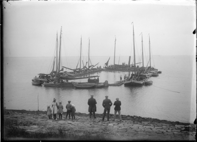 GN5114 Op een onbekende locatie liggen schepen afgemeerd voor het plaatsen van een zinkstuk van rijshout; ca. 1920