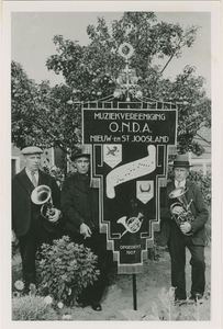 A-1418II Drie leden bij het vaandel van de muziekvereniging O.N.D.A. te Nieuw- en Sint Joosland