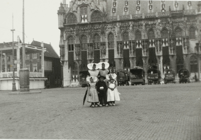 A-2028B Twee vrouwen en drie kinderen in Walcherse dracht op de Grote Markt met op de achtergrond het stadhuis met uit ...