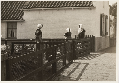 A-248 Drie vrouwen (van wie één met daagse ondermuts) in Zuid-Bevelandse dracht staande in de Zomerstraat te Ellewoutsdijk