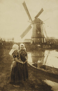P-1279 Molen Aagtekerke. Zeeland (Holland). Twee meisjes in dracht te Aagtekerke. Op de achtergrond een bootje met een ...