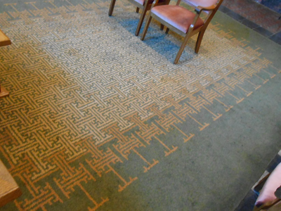 18 Groot groen vloerkleed met roodbruine en gele abstracte motieven, gelegen op de vloer van de Trouwzaal. Het zal ...