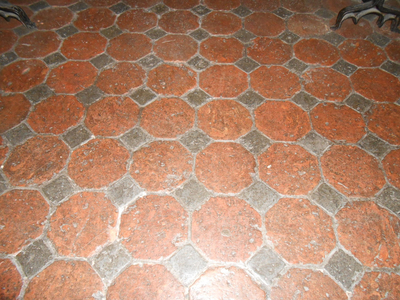 323 Plavuizen vloer onder de schouw, bestaat uit grote, achthoekige, baksteenrode tegels en kleine, vierkante, zwarte tegels