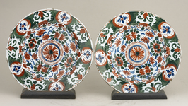 51 Twee polychroom aardewerken bordjes (geglazuurd). Delft. Gedecoreerd (groen, blauw, rood) met floraal decor