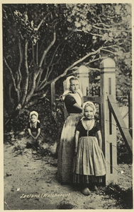 2053 Zeeland (Walcheren). Drie meisjes in Walcherse dracht bij een houten hek aan de noordzijde van boerderij ...