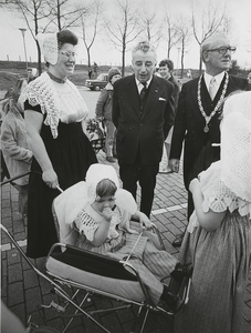656 De commissaris der Koningin mr. J. van Aartsen en burgemeester A. de Kam bij een vrouw en kinderen in klederdracht ...