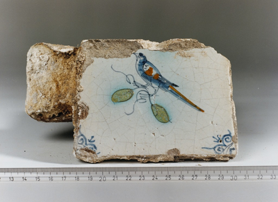 865 Brokstuk van een muur met deel van een wandtegel, waarop een vogel is afgebeeld