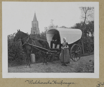 3-34 Walcherse huifkar met echtpaar in klederdracht, met daar achter de toren van de Nederlandse Hervormde kerk te ...