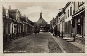 10228 Wissenkerke. Kerkstraat. Gezicht in de Kerkstraat te Wissenkerke (Noord-Beveland) met winkels, poserende personen ...