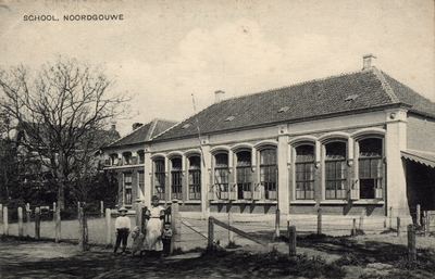 10256 School, Noordgouwe. De (openbare) lagere school te Noordgouwe met een vrouw met drie kinderen voor het hek