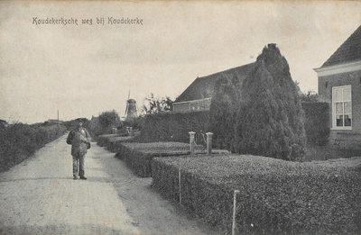 497 Koudekerksche weg bij Koudekerke. Poserende postbode op de Koudekerkscheweg te Koudekerke met op de achtergrond de molen