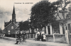 7707 Dorpstraat St.-Jansteen. Gezicht op de Dorpstraat te Sint Jansteen. Op de voorgrond een man met een duivenkorf aan ...