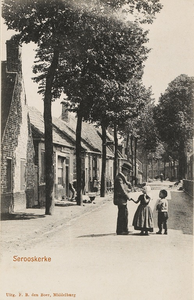 853 Serooskerke. Gezicht op een straat te Serooskerke (Walcheren) met op de voorgrond kinderen in klederdracht die een ...