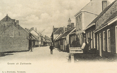 8689 Groete uit Zuidzande. Gezicht op de Dorpsstraat te Zuidzande met rechts het torentje van de Ned. Herv. kerk en ...