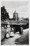 9182 Walchersch Dorpsgezicht. Een paar vrouwen en meisjes in Walcherse dracht met op de achtergrond de kerktoren van ...