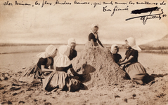 9236 Kasteeltje bouwen in het zand. Een groep meisjes in Walcherse dracht bouwt een zandkasteel op het strand
