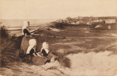 9241 Domburg, (Walcheren). Drie meisjes in Walcherse dracht in de duinen, op de achtergrond ligt Domburg
