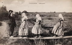 9242 Walcheren - Zeeland. Drie meisjes in Walcherse dracht op een plank over een sloot worden verwelkomd door een jongen