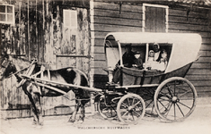9267 Walchersche huifwagen. Een Walcherse verewagen met daarin een gezin in Walcherse dracht voor een boerenschuur