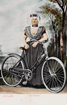 9333 Zeeland Zuid-Beveland. Een poserende vrouw in protestantse, Zuid-Bevelandse dracht met een fiets, voor een ...