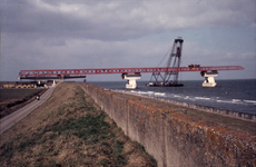 321-73 Bouw van de Zeelandbrug over de Oosterschelde : Het hijsen van de montageligger op het landhoofd