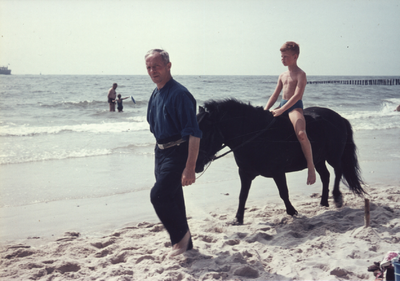 435-49 Een jongen op een pony wordt langs de vloedlijn geleid op het strand van Zoutelande