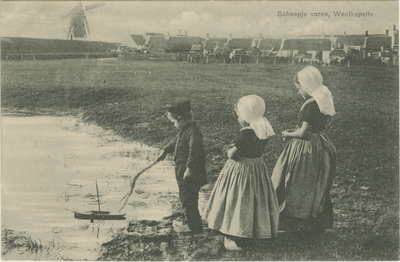 455-1150 Scheepje varen, Westkapelle. Kinderen in dracht spelen met een bootje bij een veedrinkput in een wei te Westkapelle