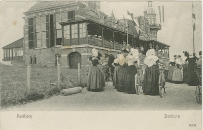 455-512 Paviljoen Domburg. Vrouwen in klederdracht, waarvan twee met een fiets, bij het Badpaviljoen te Domburg