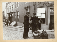 480-6 Twee mannen, waarvan één met een juk, op de hoek Markt-Pottenmarkt ter hoogte van café De Vriendschap te Middelburg