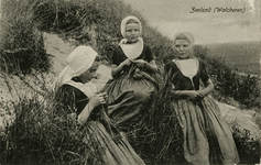 600-110 Zeeland (Walcheren). Drie meisjes in dracht aan het breien in de duinen op Walcheren