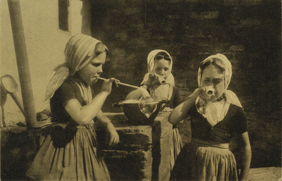 624-91 Bellen Blazen. Drie meisjes in dracht uit Westkapelle die aan het bellen blazen zijn; v.l.n.r.: Martina ...