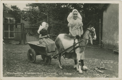94-109 Walchersche Kleederdracht (Zeeland). Uit rijden. Twee meisjes in dracht met een bokkenwagen. Het rechter meisje ...
