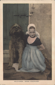 111-213 Walcheren. Goede KameradenEen meisje in Walcherse klederdracht met haar hond bij een deur van een boerderij