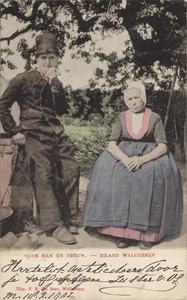 111-38 Oude man en vrouw. - eiland WalcherenEen man en vrouw in Walcherse klederdracht bij het hek van een boerderij