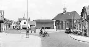 B-1265 Bruinisse. Korte Ring. Gezicht op de muziektent en de Ned. Herv. Kerk, met rechts de winkel in huishoudelijke ...