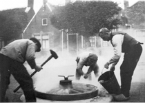 D-0011 Ouwerkerk. Dorpsring. Smederij Giljamse. Vastleggen van de ijzeren band om het houten wiel voor een boerenwagen. ...