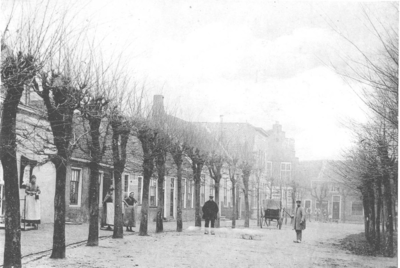 D-0023 Ouwerkerk. Ring. Zuidzijde van de Ring. Links het gemeentehuis, met daarvoor de vrouw van de veldwachter, M. ...