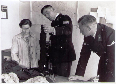 X-5153 Nieuwerkerk. Wachtmeester C.J. Papeveld en collega tonen kleding ter identificering van slachtoffer